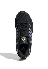 Svart sportskor med överdel i mesh, med grå ränder och gröna accenter. Inkluderar rund snörning och en vadderad krage.