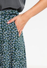 Hame floral-muotoilulla vihreänä, sinisillä ja valkoisilla kuvioilla. Kevyt, rento malli ja sivutaskut.