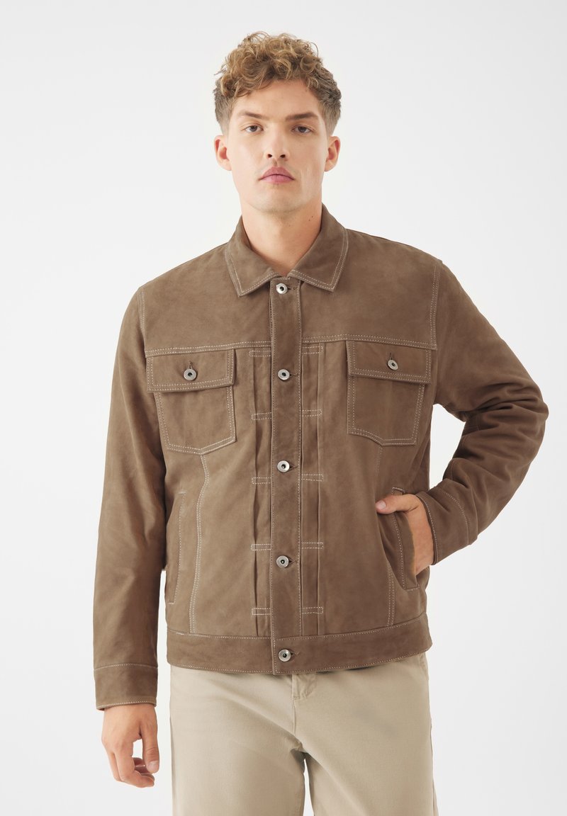 Hnědá semišová bunda s knoflíkovým zapínáním, dvěma náprsními kapsami a bočními kapsami. Má kontrastní bílé švy a klasický design límce.