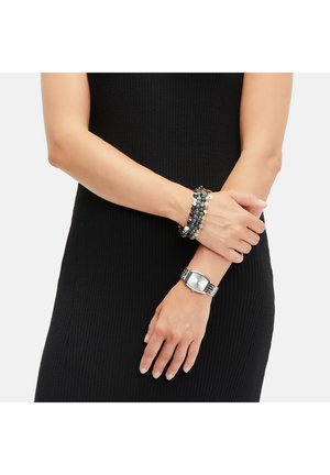 Silberne Uhr mit rechteckigem Zifferblatt auf einem Metallarmband, kombiniert mit einem mehrsträngigen Perlenarmband in Blau- und Grautönen.