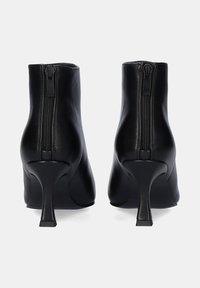 Botines de cuero negro con un diseño elegante, punta afilada y tacón alto. Cuentan con una cremallera en la parte posterior para facilitar su uso.