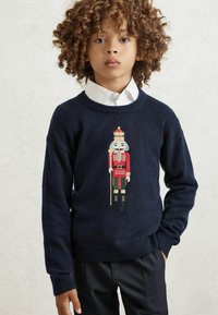 Tamsiai mėlynas megztinis su graužikų dizainu raudona, žalia ir auksine spalvomis. Turi apvalų kaklą ir raukšlėtus rankogalius bei apatinę dalį.