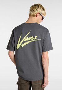 Camiseta de algodón gris con un gran gráfico del logo "Vans" en amarillo en la parte de atrás, de mangas cortas y corte relajado.