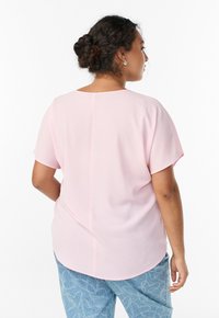 Ružový top s krátkymi rukávmi, okrúhlym výstrihom a rovno šitým chrbtom, v kombinácii s svetlomodrými džínsami so vzorom srdiečok.