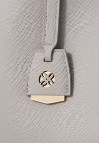 Borsa a tracolla grigia con texture, caratterizzata da dettagli in metallo dorato e una chiusura decorativa con design floreale. Include una tracolla abbinata.