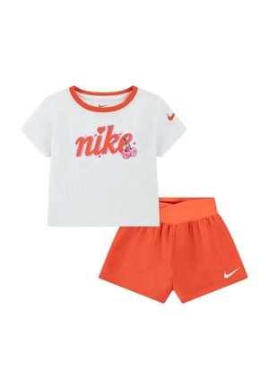 Camiseta blanca de manga corta con cuello naranja y texto "nike" con corazones, combinada con pantalones cortos naranjas con un pequeño logo blanco de Nike.