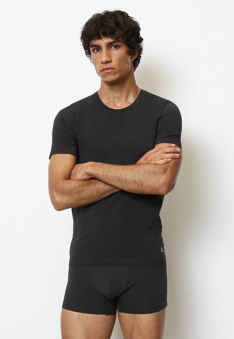 Sort tætsiddende t-shirt med korte ærmer og rund halsudskæring, parret med matchende sorte boxershorts, præsenteret på en neutral baggrund.