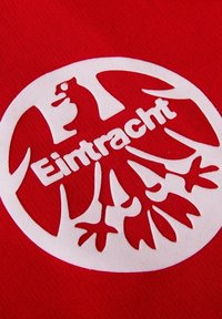 Rode stof met een wit cirkelvormig logo met een adelaarontwerp en de tekst "Eintracht" onderaan. De textuur is soepel.