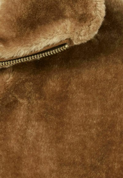Tejido de piel sintética marrón con una textura suave, que cuenta con un zipper de metal a lo largo del borde para el cierre y detalles decorativos.