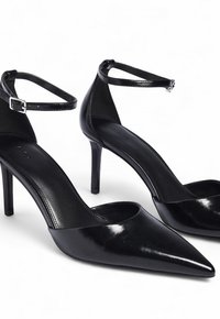 Mustad mustad kõrged kontsad terava varbaga, läikivast patentnahast, pahkluu rihmaga ja stilletto kontsaga, millel on sile tekstuur ja minimaalne disain.