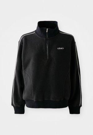 Zwart fleece pull met een hoge kraag, rits aan de voorkant tot de helft, witte zijkanten en een klein logo op de borst. Zachte textuur, losse pasvorm.