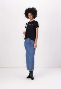 Black cotton t-shirt with graphic design, paired with a high-waisted denim skirt, and black ankle boots. Simple and casual attire.