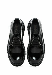Chaussures en cuir noir avec une finition brillante, à bout rond et semelle texturée. Présentent six œillets et une doublure intérieure texturée.