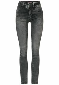 Jeans ajustados en denim negro desgastado, con una cintura alta, cierre de dos botones y diseño clásico de cinco bolsillos. Textura suave con un desgaste sutil.