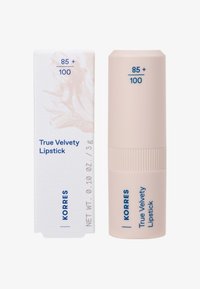 Rouge à lèvres Korres True Velvety dans un tube cylindrique rose clair, avec du texte bleu. Accompagné d'une boîte blanche avec un motif doux.