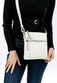 Vit syntetisk crossbody-väska med en framficka med dragkedja, rektangulär form och justerbar axelrem. Slät yta med subtil branding.