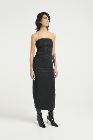 Black strapless midi dress with shimmering texture, fitted silhouette, and subtle sparkles, paired with glossy black pointed boots.
