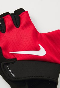 Gant de musculation sans doigts rouge et noir avec tissu en mesh, logo Nike en blanc et prise texturée sur la paume. Comprend des bords cousus et des poignets extensibles.