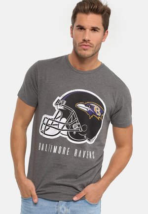 Grå T-shirt med et Baltimore Ravens hjelmlogo i sort og lilla, med tekst nedenfor. Korte ærmer og rund halsudskæring.