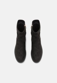 Černé kotníkové boty vyrobené z měkké semišové kůže, s elegantním designem, kulatou špičkou a bočním zipem se zlatým akcentem pro snadné obouvání.