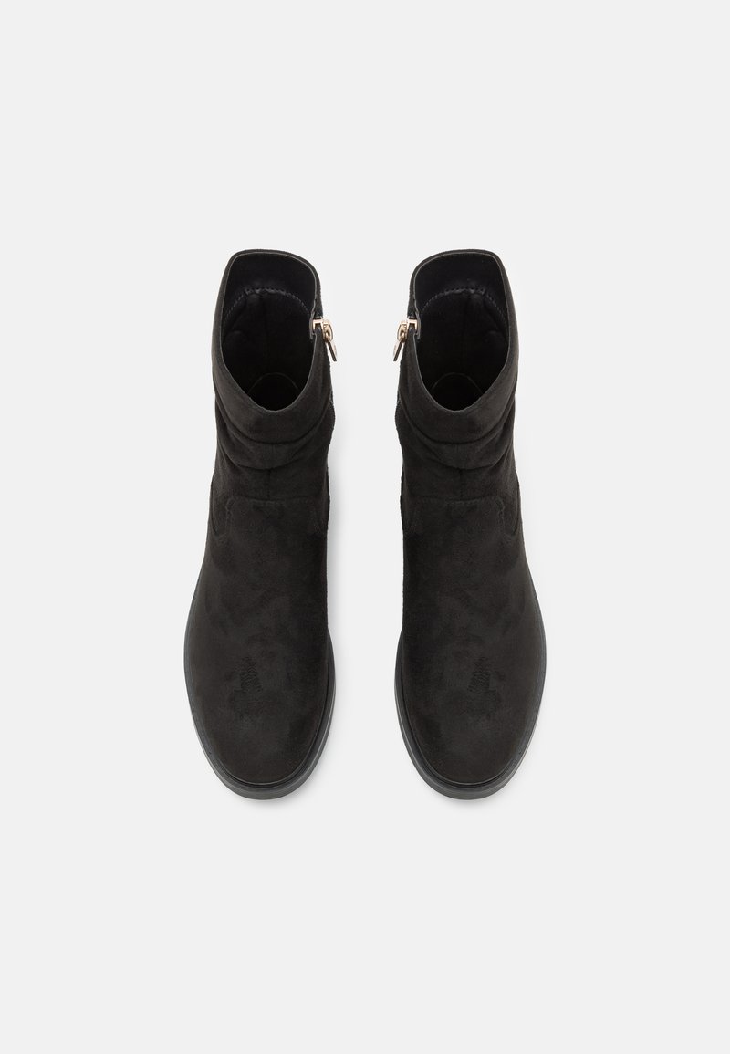 Schwarze Knöchelstiefel aus weichem Wildleder, mit einem eleganten Design, runder Spitze und einem seitlichen Reißverschluss mit goldener Akzentuierung für einfaches An- und Ausziehen.
