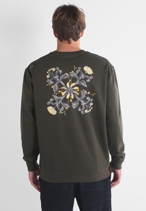 Sweatshirt vert olive avec un motif floral au dos, comprenant des fleurs grises et jaunes, à manches longues, avec des bordures côtelées aux poignets et à l'ourlet.