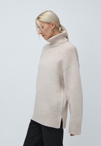 Ροζ ανοιχτό oversized πουλόβερ με εσωτερικό λαιμό σε μαλακό μάλλινο υλικό, με ραβδωτές λεπτομέρειες, πλαϊνές σχισμές και άνετη γραμμή.