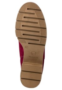Semelle d'une chaussure bordeaux avec un fond en caoutchouc texturé. Présente des rainures horizontales et des motifs circulaires pour l'adhérence. Taille indiquée comme 37.