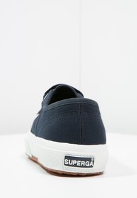 Námořnické plátěné tenisky s bílou gumovou podrážkou, s texturovaným povrchem a logem "SUPERGA" na patě. Jednoduchý design, nízký profil.