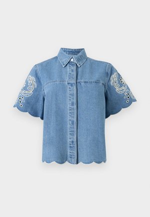 Chemise à manches courtes en denim bleu avec bords festonnés et broderie florale blanche sur les manches, fermeture à boutons sur le devant et col classique.