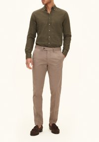 Olijfgroene geknoopte blouse, beige chino's en donkerbruine instappers. Katoenen stof, getailleerde pasvorm, met een soepele textuur en klassiek ontwerp.