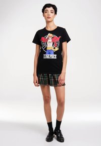 Black cotton t-shirt featuring a colorful graphic of a character from "One Piece," paired with a plaid mini skirt and black shoes.