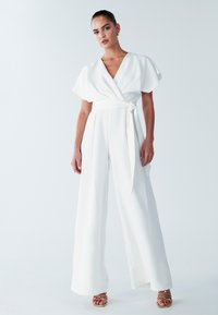 Witte jumpsuit met een wikkelmodel aan de voorkant, korte vlindermouwen en een ceintuur in de taille. Wijde, vloeiende broekspijpen en een gladde textuur.
