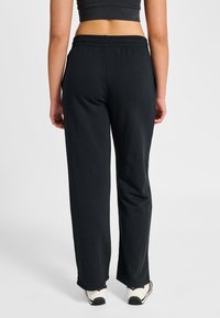 Svarta mjukisbyxor med avslappnad passform, elastisk midja, sidofickor och subtila sömdetaljer. Tillverkade av ett mjukt, stretchigt tyg.