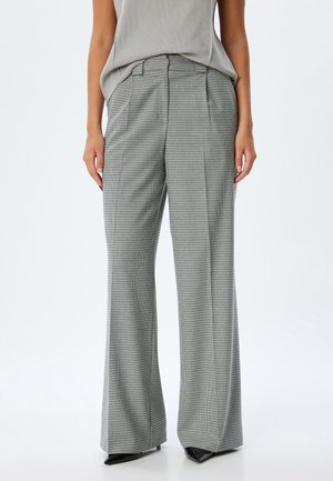 Pantalones de pierna ancha con patrón de cuadros en gris, elaborados en tela texturizada, con una cintura alta y pleques ajustados. Combinados con zapatos negros.