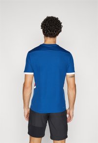 T-shirt de sport bleu à manches courtes, col rond et accents blancs contrastants. Tissu lisse avec un design ajusté.