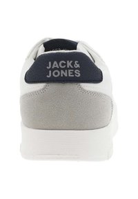 Sneaker blanche avec des accents bleu marine et gris, présentant un dos texturé, une semelle en caoutchouc blanche et le logo "JACK & JONES" affiché de manière proéminente.