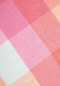 Plaid textile in pastel shades of pink, coral, and white, featuring a soft texture and large, even squares.