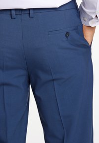 Marineblaue Hose aus strukturierter Baumwolle, mit schlanker Passform, flachem Vorderdesign und einer Gesäßtasche mit schwarzem Knopfdetail.