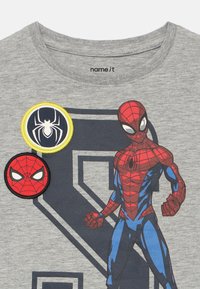 Szary bawełniany t-shirt z dużą nadrukowaną grafiką Spider-Mana w czerwieni i błękicie oraz czarno-żółtymi naszywkami haftowanymi nad wzorem.