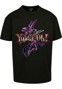 Juodas medvilnės marškinėliai, ant kurių pavaizduotas violetinis personažas su lazda, o žemiau raudonai ir auksškai užrašyta "Yu-Gi-Oh!".