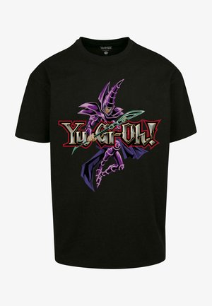 T-shirt di cotone nero con una grafica di un personaggio viola che impugna un bastone, con il testo "Yu-Gi-Oh!" in rosso e oro sottostante.
