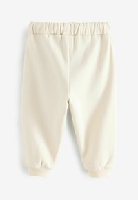 Pantalons de survêtement couleur crème avec une taille élastique, des poignets fuselés et un tissu doux, idéaux pour le confort et le port décontracté.