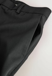 Pantaloni din țesătură neagră cu o textură netedă, având un tiv pliat și un design frontal plat. Brâu simplu, fără elemente metalice vizibile.