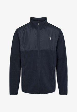 Mornarsko flis jakna s kontrastnim najlonskim panelom na vrhu, zadrgo, stoječim ovratnikom in stranskimi žepi. Ima manjši logotip na prsih.