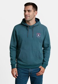 Teal gestreepte hoodie met een voorkantzak, trekkoord in de capuchon, en een logo patch op de borst. Gemaakt van zachte, gestructureerde stof met geribbelde manchetten.