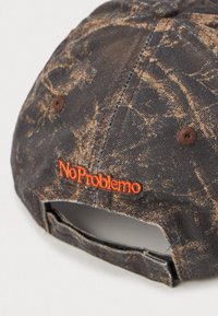 Abgenutzte schwarz-braun marmorierte Baseballmütze mit verstellbarem Riemen und orangefarbener gestickter "No Problemo"-Schrift auf der Rückseite.