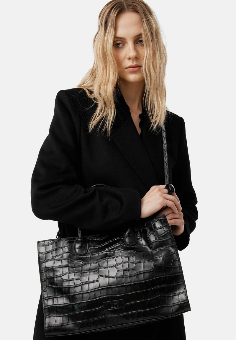 Borsa nera in pelle con stampa coccodrillo, texture in pelle liscia, doppio manico superiore e tracolla rimovibile. Presenta una base piatta.
