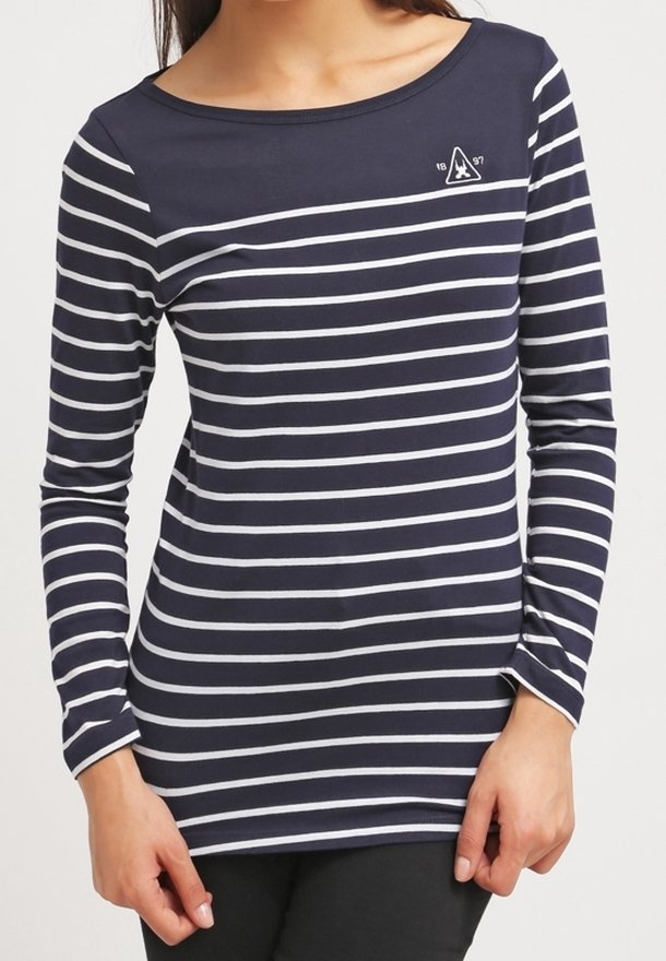 Woman wearing a navy blue long-sleeve shirt with white horizontal stripes and a small white emblem on the upper chest.