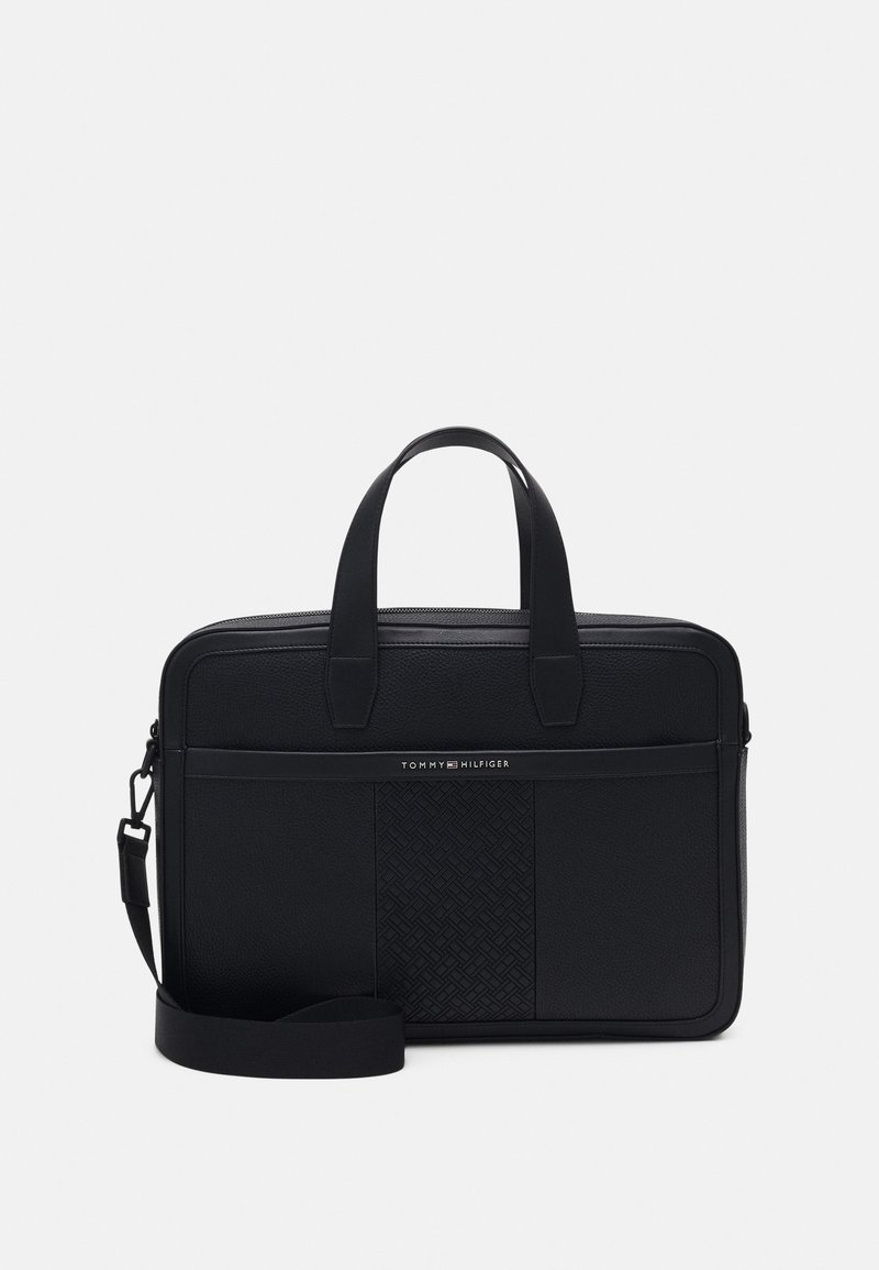 Mallette en cuir noir avec double poignée, bandoulière réglable, panneau central texturé et petit logo Tommy Hilfiger sur la poche avant.